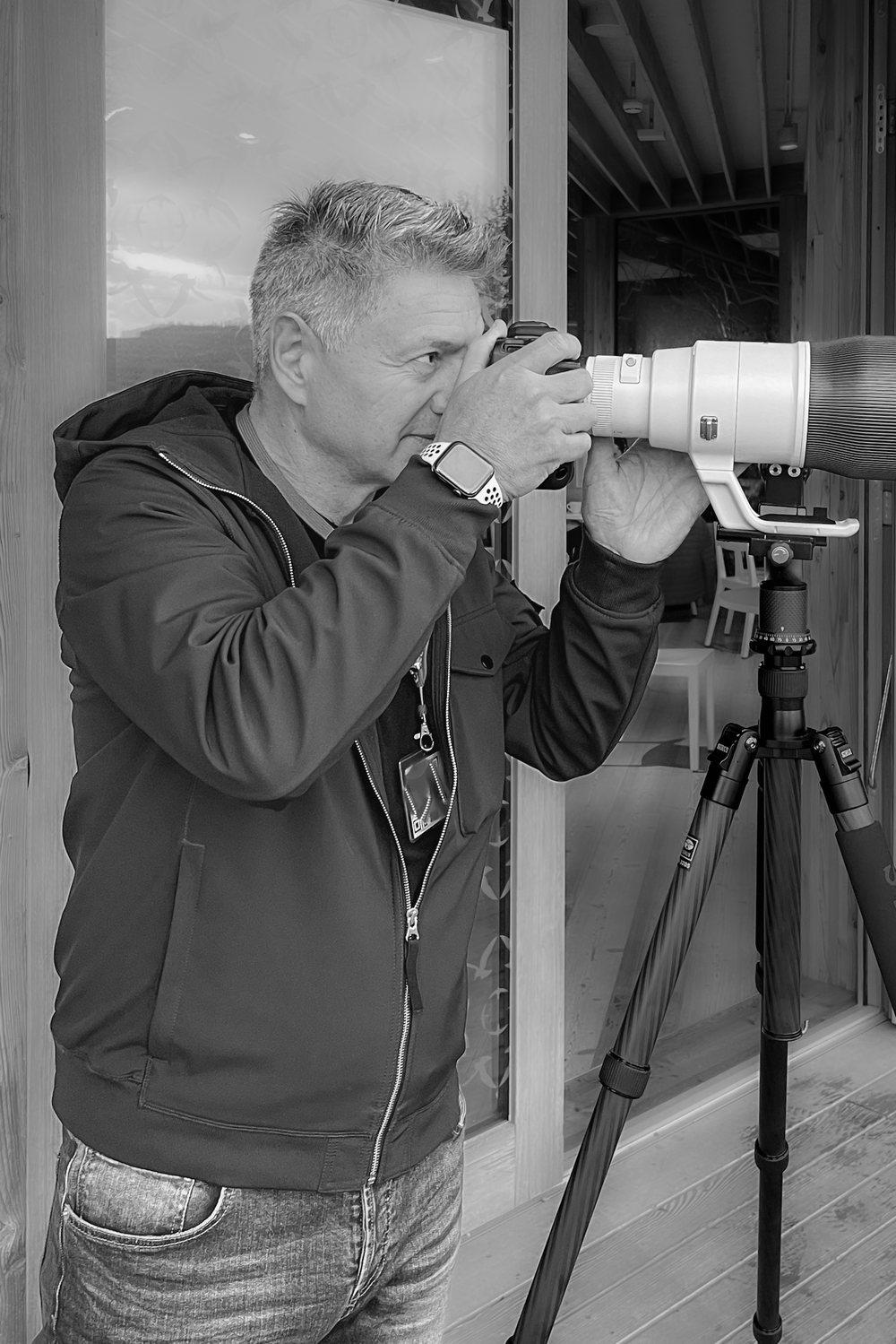 Fotograf mit Kamera und Teleobjektiv auf Stativ